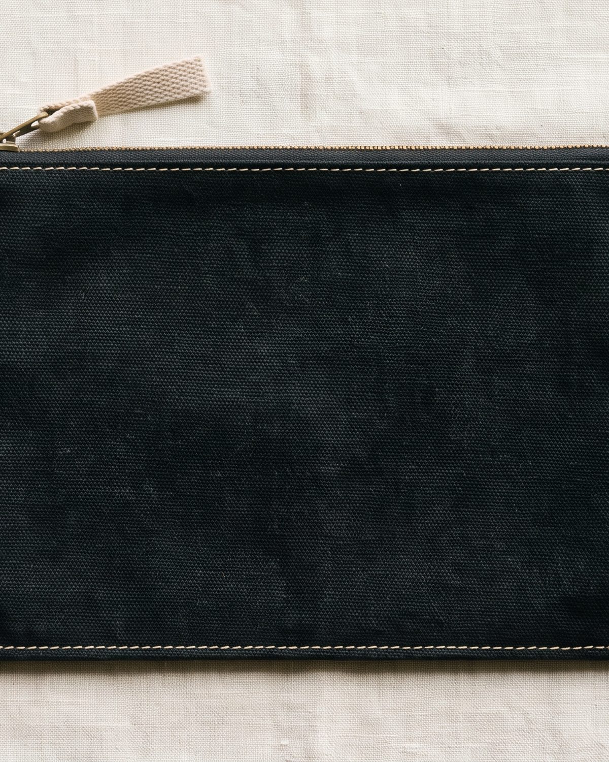 Pochette plate en toile de coton teintée noir encre, zip métal et tirette en sangle